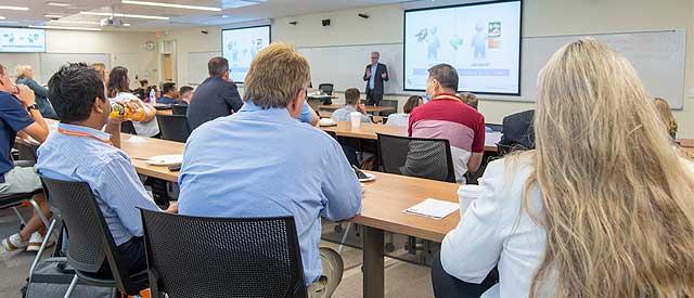 a group of people in a Carroll University classroom listening to a presenter.